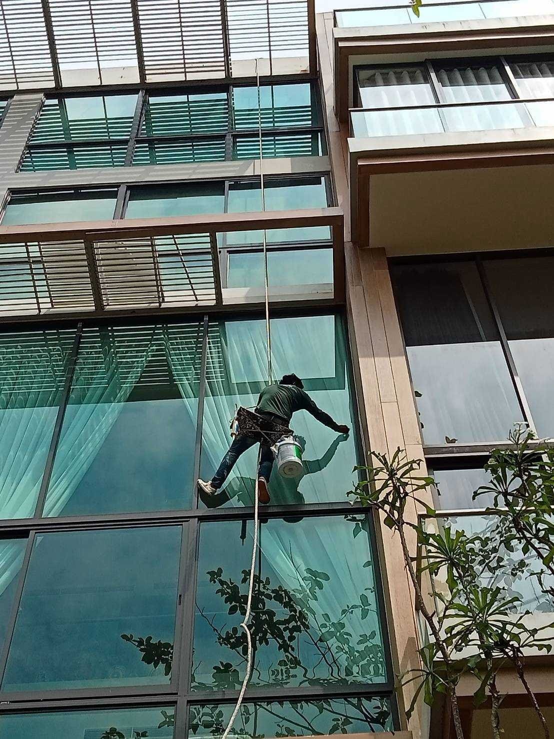 ช่างโรยตัวทำงานบนผนังกระจกด้านนอกอาคารหลายชั้น